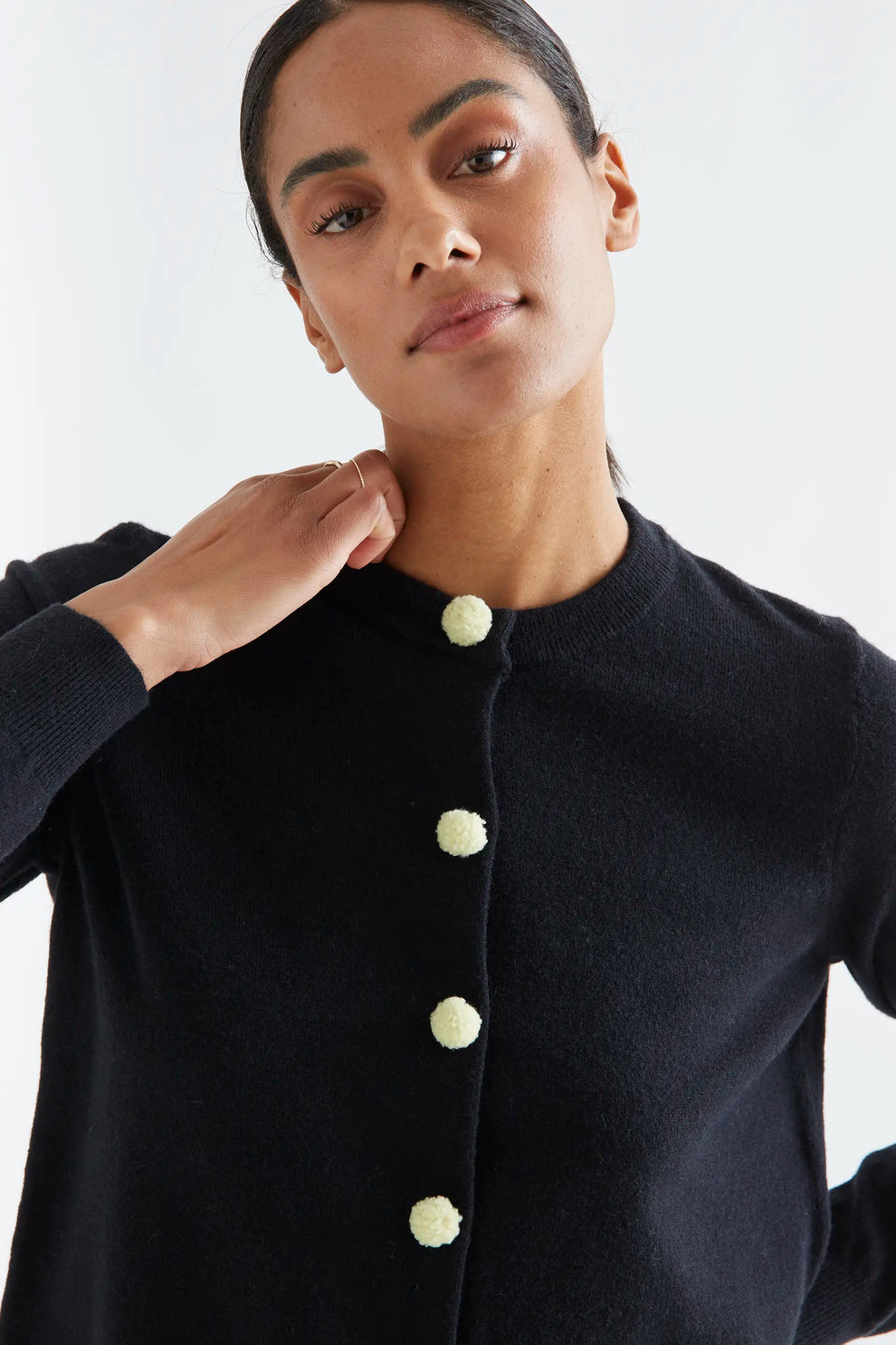 Cardigan nero con pon pon gialli
